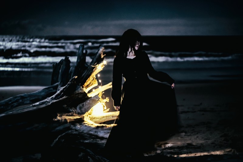 夜の海で踊る黒服の女性